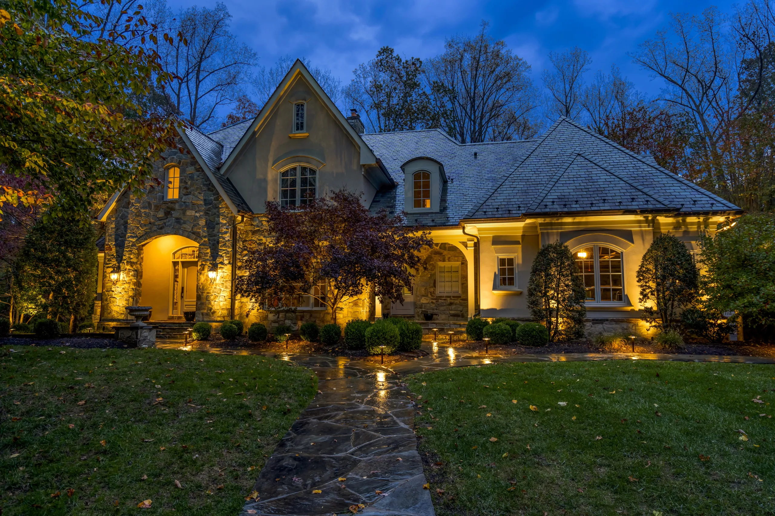 Exterior shot of home at night being illuminated by outdoor landscape lighting
