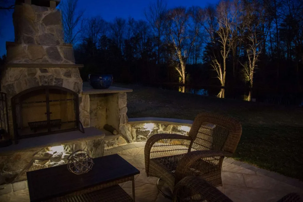 Backyard patio with fireplace and landscape lighting. Illuminated in the evening. Property value