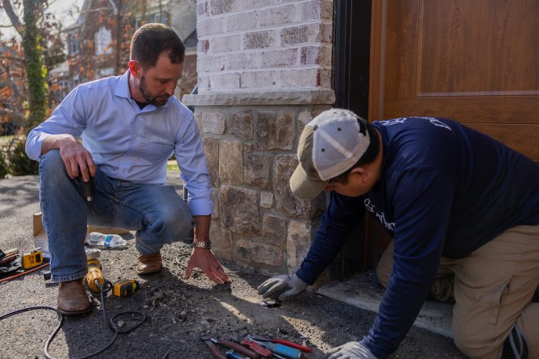 Dayloom founder Patrick Harders, LC, and a crew member setting an in-ground light fixture beside a stone wall in McLean.
