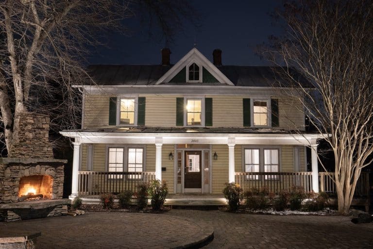 Dayloom office in Aldie, Loudoun County, VA: farmhouse-style facade with lit porch columns, stone fireplace glow and garden lighting