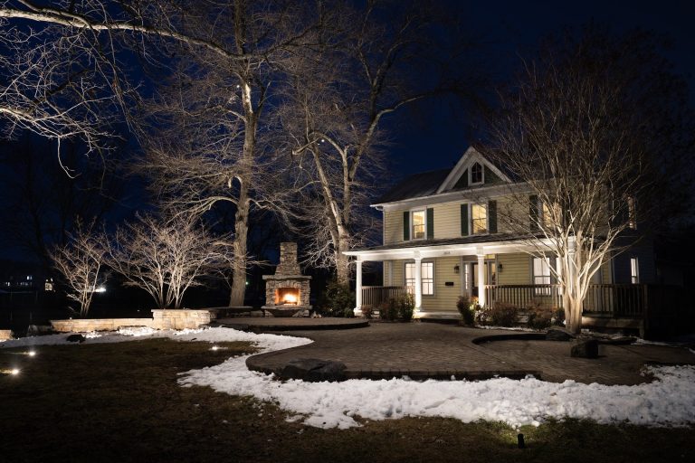 Dayloom office in Aldie, Loudoun County, VA, with uplit mature trees, lit porch and snow on the lawn at night