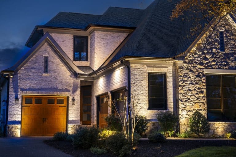 Landscape lighting on a modern McLean, VA home with a stone facade and lit garage