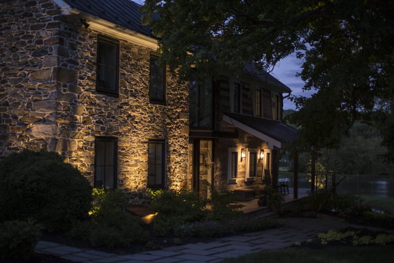 Close view of a stone farmhouse with lit facade, porch and stone walkway at twilight in western Loudoun County